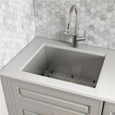 a stainless steel sink in a kitchen with hexagonal tiles on the wall