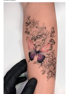 a woman's arm with flowers and a butterfly on it, while she is wearing gloves