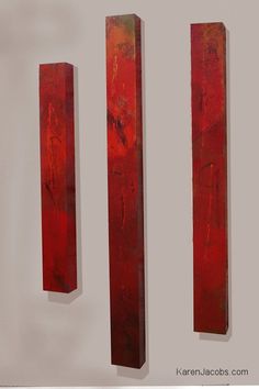 three pieces of red wood are hanging on the wall