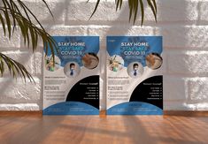 two flyers for a stay home covidi is displayed on a wooden floor in front of a white brick wall