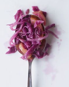 a spoon filled with red cabbage on top of a white table