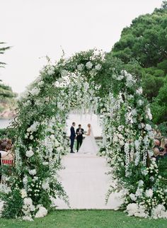 a bride and groom are walking down the aisle at their wedding ceremony with white flowers