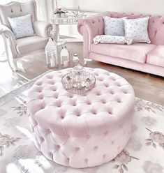 a living room filled with pink furniture and pillows on top of a white carpeted floor