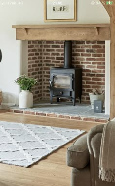 a living room with a brick fireplace and rugs in front of the fire place