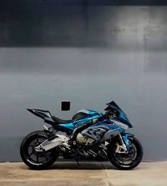 a blue motorcycle parked in front of a gray wall