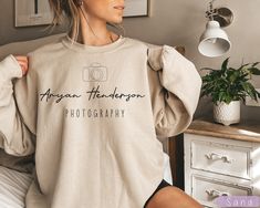 Are you a photographer? Do you love taking pictures of your friends and family? Well, then this personalized photography sweatshirt is perfect for you! Not only will it keep you warm during cold weather shoots, but it also features your very own custom name on the back. Who knows, maybe someone will recognize you from one of your amazing shots! So why not pick up a sweatshirt today and show everyone just how talented you are? |Personalized Photography Sweatshirt, Custom Name Photography Sweatshirt, Photographer Gift, Photographer Custom Logo| IMPORTANT INFO: Shirt and graphic colors may slightly vary depending on your screen settings or the color you choose.  Please see all of our shop policies and FAQ information for any other information. If you still have any unanswered questions please Photography Sweatshirt, Gift For Photographer, Unanswered Questions, Photographer Gifts, Gifts For Photographers, Your Amazing, Shoot Ideas, Who Knows, Pictures Of You