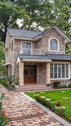 a stone house in the middle of a lush green yard with lots of trees and flowers