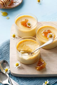 three small desserts are sitting on a cutting board with spoons next to them