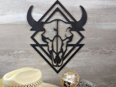 a cowboy hat sits next to a metal bull head on a wall with a geometric design