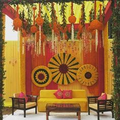 a decorated stage with yellow and red decor on it's walls, flowers hanging from the ceiling