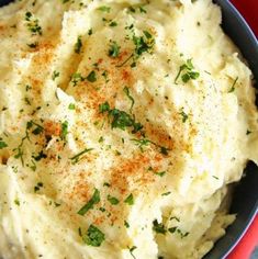 mashed potatoes with parsley and seasoning in a blue bowl on a red cloth