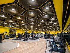 a gym with treadmills, exercise machines and other equipment in the area that is yellow