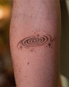 a person with a small tattoo on their arm that has an image of a black hole in it