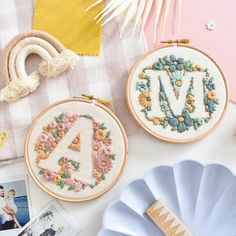 two embroidered hoop frames sitting on top of a table next to pictures and other items