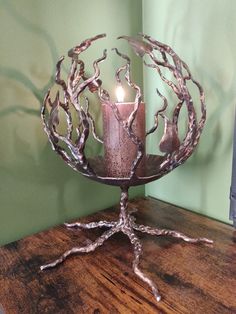 a candle sits on top of a table next to a tree branch sculpture with a lit candle in it