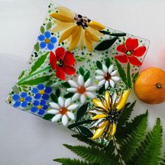 a glass plate with flowers on it next to an orange