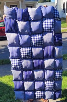 a pile of blue and white pillows sitting on top of a grass covered field next to a house