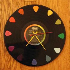 a clock made out of an old vinyl record with colored hearts on the side and yellow hands