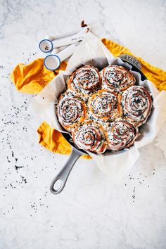 a pan filled with cinnamon rolls sitting on top of a table next to scissors and napkins