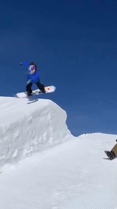 two snowboarders are doing tricks in the snow