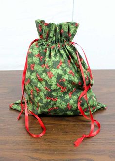 a drawstring bag sitting on top of a wooden table next to a red ribbon