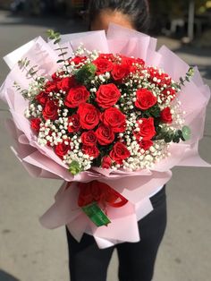 a woman holding a bouquet of red roses