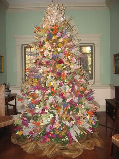 a decorated christmas tree in a room with blue walls and wooden flooring, along with an ornate chandelier