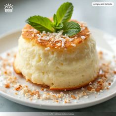 a small dessert on a white plate with sprinkles and green leafy garnish