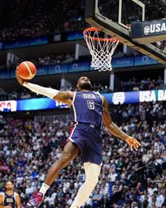 a basketball player dunking the ball in front of an audience at a sporting event