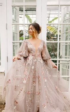 a woman standing in front of a window wearing a long dress with flowers on it