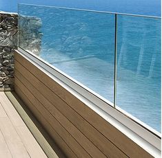 a wooden bench sitting on top of a balcony next to the ocean with a glass railing