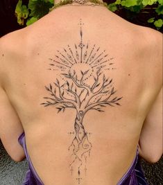 the back of a woman's neck with a tree tattoo on it