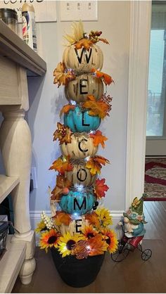 a tall vase filled with lots of pumpkins and fall leaves sitting on top of a table