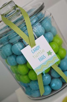 a jar filled with blue and green candies next to a sign that says candy turtle eggs