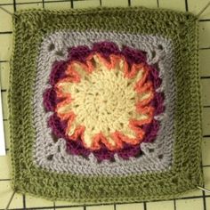 a crocheted square with an orange and yellow center