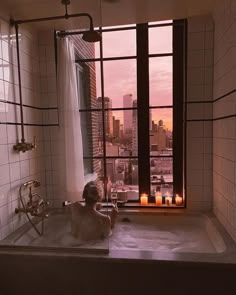 a bath tub sitting next to a window with candles on the outside and in front of it