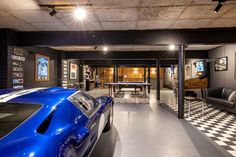 a blue sports car is parked in a garage with checkered flooring and black walls