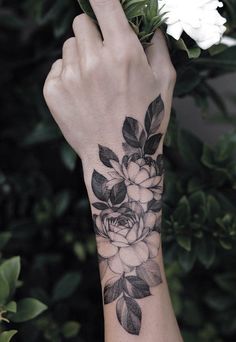 a woman's arm with a flower tattoo on it and leaves around her wrist