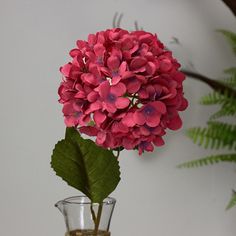 a vase filled with pink flowers sitting on top of a table next to a plant