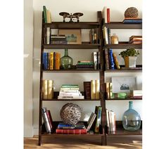 a bookshelf filled with lots of books on top of a hard wood floor