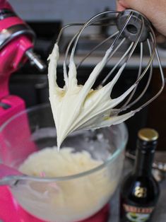 a hand holding a whisk over a mixing bowl filled with batter and cream