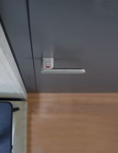 a close up of a door handle on a cabinet with wood flooring and gray walls