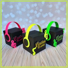 three black boxes with neon colored headphones in them on a wooden table next to a blue and white polka dot background