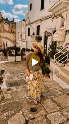 a woman in a yellow dress and straw hat standing on the steps of an old building