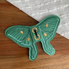 a green leather butterfly key fobring on a wooden surface