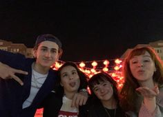 four people posing for a photo with lights in the background