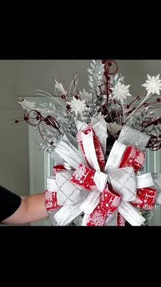 someone is holding a red and white christmas wreath