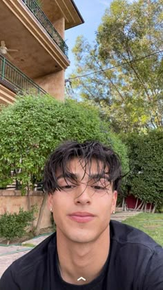 a young man with wet hair sitting in front of a building and looking at the camera