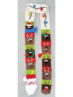 a knitted christmas scarf with santa claus and reindeers on it, hanging from the side