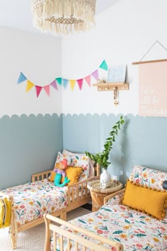 two beds in a room with blue walls and colorful decorations on the wall above them